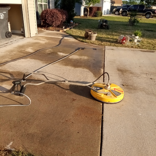 A concrete driveway being pressure washed.