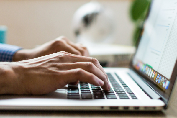 A close up of hands typing on a laptop