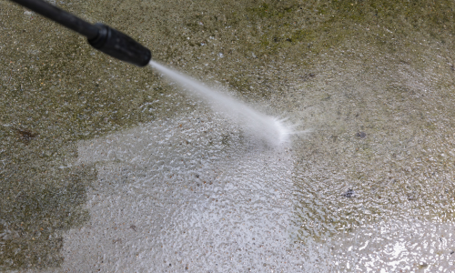 The close up of a pressure washer being used.