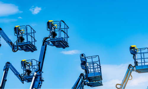 A line of blue boom lifts on a clear day.